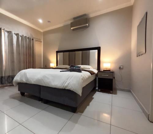 a bedroom with a large bed and a nightstand with two lamps at Viking Guest House in Mahikeng