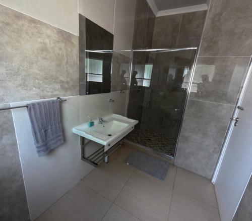 a white bathroom with a shower and a sink at Viking Guest House in Mahikeng