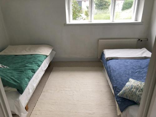 two beds in a small room with a window at Vejlø Skole - Degnegaarden in Næstved