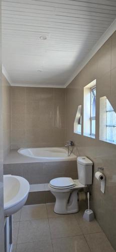 a bathroom with a tub and a toilet and a sink at Relax Guest House in Goodwood