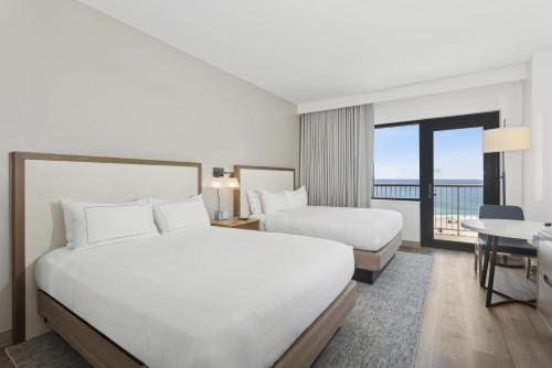 a hotel room with two beds and a balcony at The Lodge at Gulf State Park, A Hilton Hotel in Gulf Shores