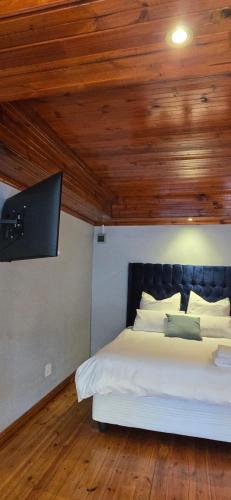 a bedroom with a white bed with a wooden ceiling at Relax Guest House in Goodwood