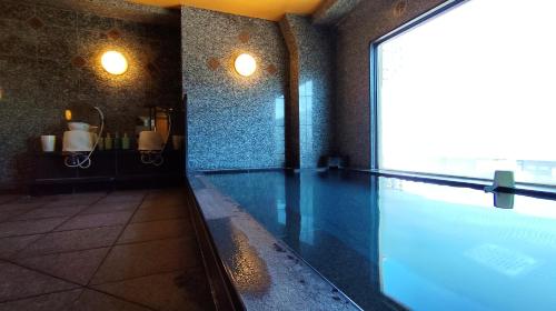 a swimming pool in a room with a large window at Hotel Route-Inn Yokohama Bashamichi in Yokohama