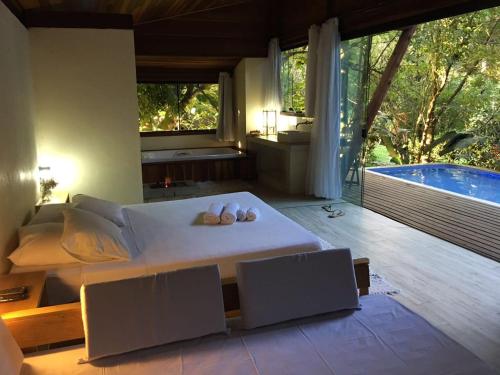 a bedroom with a large bed and a tub at Residencial Warabi in Visconde De Maua