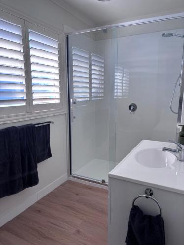a white bathroom with a shower and a sink at Five Little Ducks in Adventure Bay