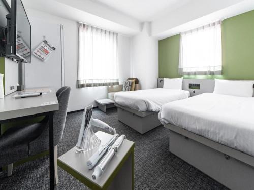 a hotel room with two beds and a desk at Henn na Hotel Tokyo Ginza in Tokyo