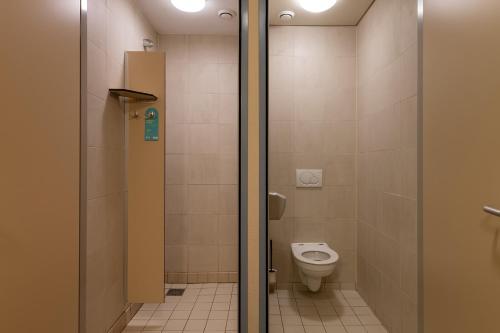 a bathroom with a toilet and a shower stall at Stayokay Hostel Texel in Den Burg