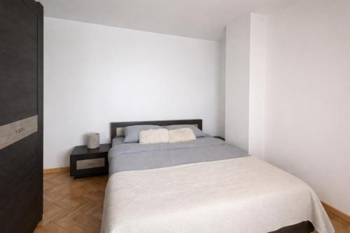 a bedroom with a bed in a white room at Sara Apartment Centru Râmnicu Vâlcea in Râmnicu Vâlcea