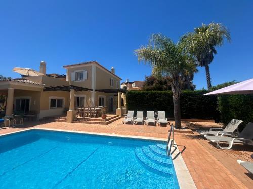 a swimming pool with chairs and a house at Perfect Golf & Beach Villa for 8 people in Estômbar