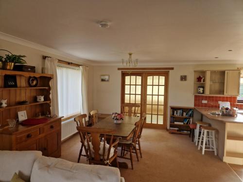 a kitchen and living room with a table and a kitchen and a table and chairs at Brandane in Brodick