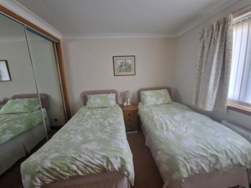 a bedroom with two beds and a window at Brandane in Brodick