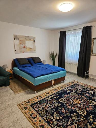a bedroom with a blue bed and a rug at BiRo-Apartments in Zalavár