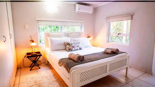 a bedroom with a white bed with two pillows on it at Beach Forest Lodge - Milkwood in Ballito