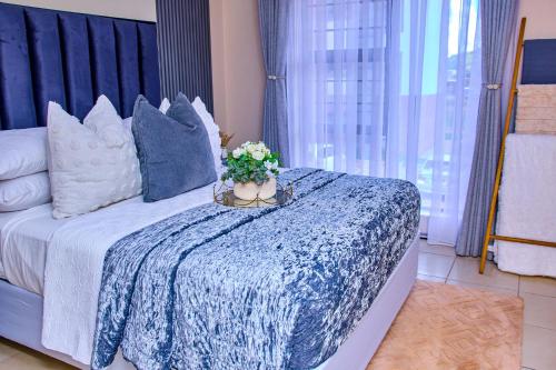a bedroom with a bed with a blue blanket and flowers at Kunashe Apartments in Harare