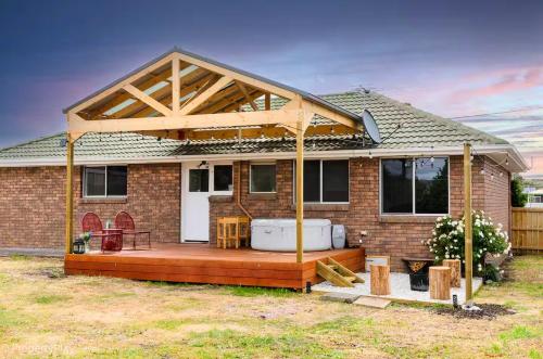 a house with a large deck with a hot tub at Hobart Family Retreat with Spa and Backyard Near Airport in Sorell