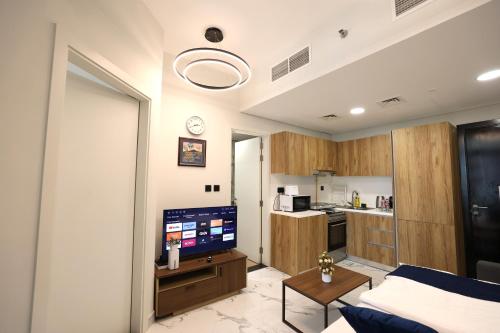 a living room with a television and a kitchen at Central Stay 1 Bed Junior near Cleveland and Abu Dhabi Mall in Abu Dhabi