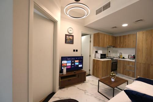 a living room with a television and a kitchen at Central Stay 1 Bed Junior near Cleveland and Abu Dhabi Mall in Abu Dhabi