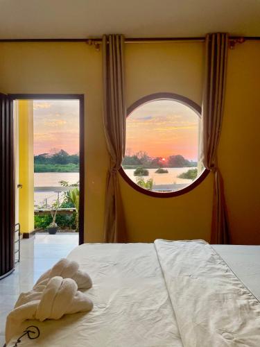 a bedroom with a bed with a large window at Tena Don Det Sunset Guest House in Don Det