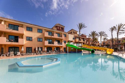 a swimming pool with a slide in front of a hotel at BLUESEA Aloe Corralejo in Corralejo