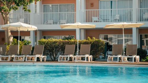 a group of chairs and umbrellas next to a swimming pool at BLUESEA Bahía de Lobos in Corralejo