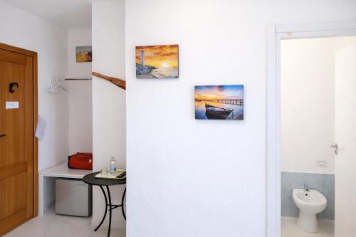 a bathroom with a toilet and three pictures on the wall at Affitta Camere di Berenice in Porto Azzurro
