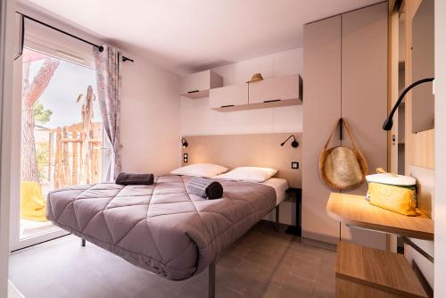 a bedroom with a large bed and a large window at Camping Les Sables d'Or in Cap d'Agde
