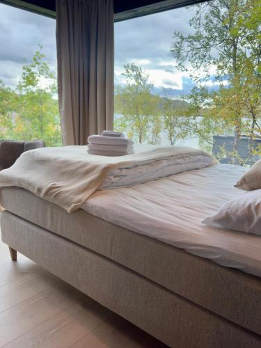 a bed in a room with a large window at Aurora Sea Lodges in Karpbukt