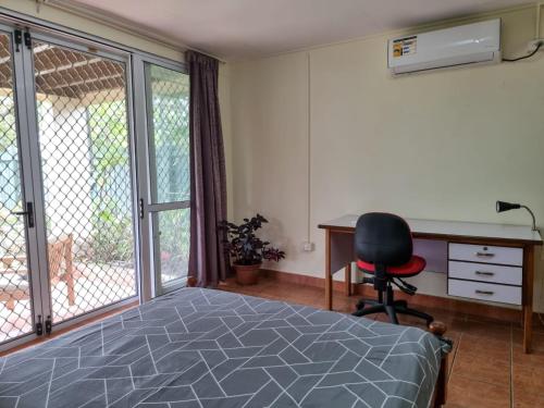 a bedroom with a bed and a desk and a chair at Panatina Hilltop Downstairs Unit in Honiara