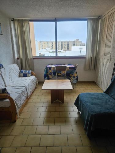 a room with a bed and a table and a window at bord de mer in Leucate-Plage
