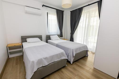 two beds in a room with two windows at Holiday Villa Lena in Köyceğiz