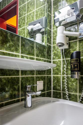 a bathroom with a white sink and a green tiled wall at Hotel Grunewald in Berlin