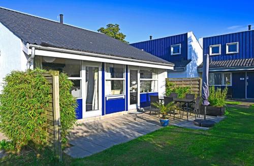 a white house with blue doors and a yard at Marielyst Nørrevang-solrig-sydvendt-centralvarme in Bøtø By