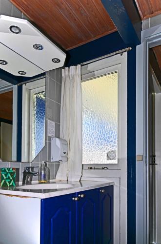 a kitchen with blue cabinets and a sink and a window at Marielyst Nørrevang-solrig-sydvendt-centralvarme in Bøtø By