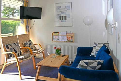 a living room with a blue couch and a table at Marielyst Nørrevang-solrig-sydvendt-centralvarme in Bøtø By