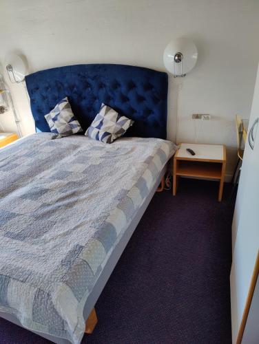 a bedroom with a large bed with a blue headboard at Marielyst Nørrevang-solrig-sydvendt-centralvarme in Bøtø By