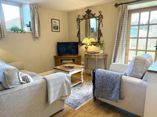 a living room with two couches and a tv at Gooseyard at Middle Farm and Cottages in Picklescott