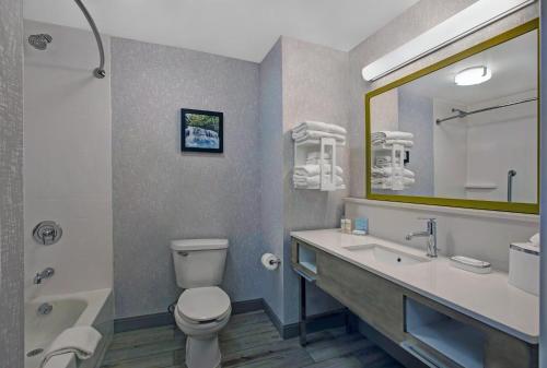 a bathroom with a toilet and a sink and a tub at Hampton Inn Westfield in Westfield