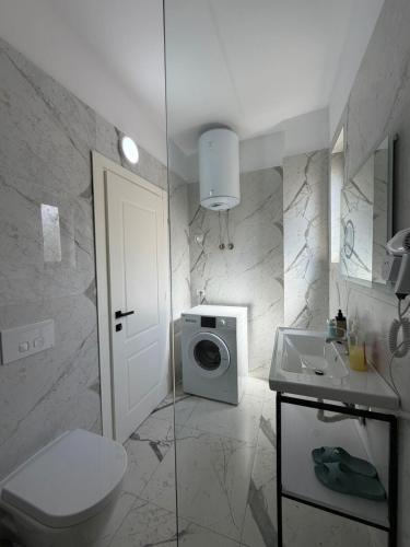 a bathroom with a toilet sink and a washing machine at Sunny Hill Residence in Vlorë