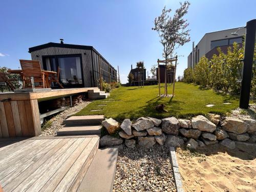 a small yard with a stone wall and a playground at Kolokemp pri súkromnom jazere Boldog in Senec