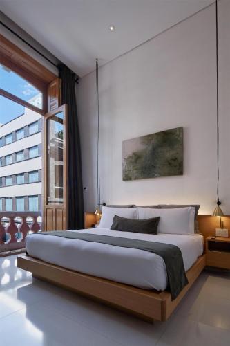 a bedroom with a large bed and a large window at Umbral, Curio Collection By Hilton in Mexico City