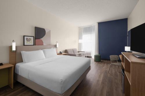a bedroom with a white bed and a living room at Spark By Hilton Florence North I-95, Sc in Florence