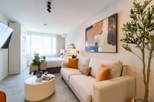 a living room with a couch and a bed at Apartamentos Plaza España - Enjoy Sevilla in Seville