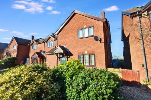 a red brick house with bushes in front of it at 18 Marriotts Way in Sheringham