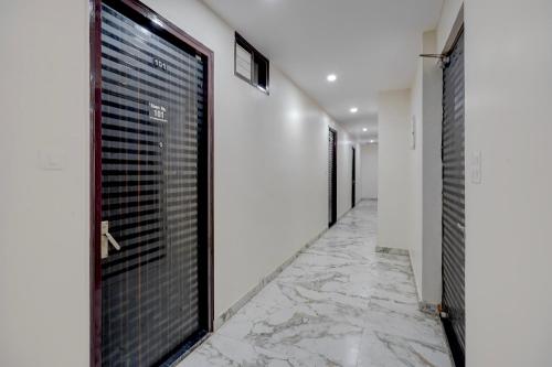 a hallway with black doors and marble floors at FabHotel Metro Inn in Kānpur