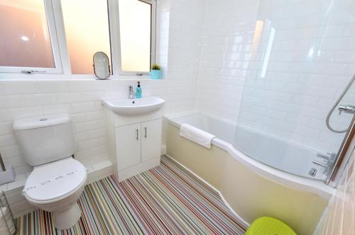 a bathroom with a toilet and a sink and a tub at 18 Marriotts Way in Sheringham