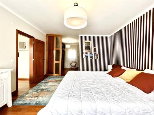 a bedroom with a large bed and a black and white striped wall at Villa Mar & Surf • Piscina privada in Atouguia da Baleia
