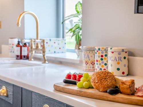 a cutting board with fruits and vegetables on a kitchen counter at 1 Bed in Gloucester oc-95793 in Tirley