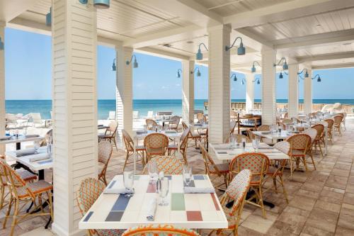a restaurant with tables and chairs and the ocean in the background at The Reach Key West, Curio Collection by Hilton in Key West