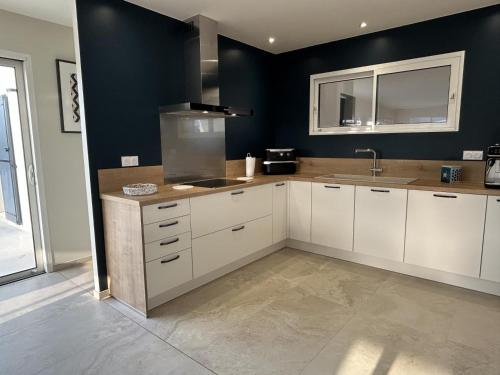 a kitchen with white cabinets and a sink at Gîte Le 10 in Neuville-du-Poitou