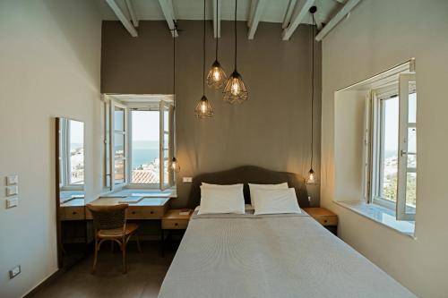 a bedroom with a bed and a desk and windows at Earino apartments in Hydra
